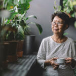peaceful senior asian chinese woman having coffee at home chillling