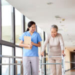 young asian physical therapist working with senior woman on walking with a walker