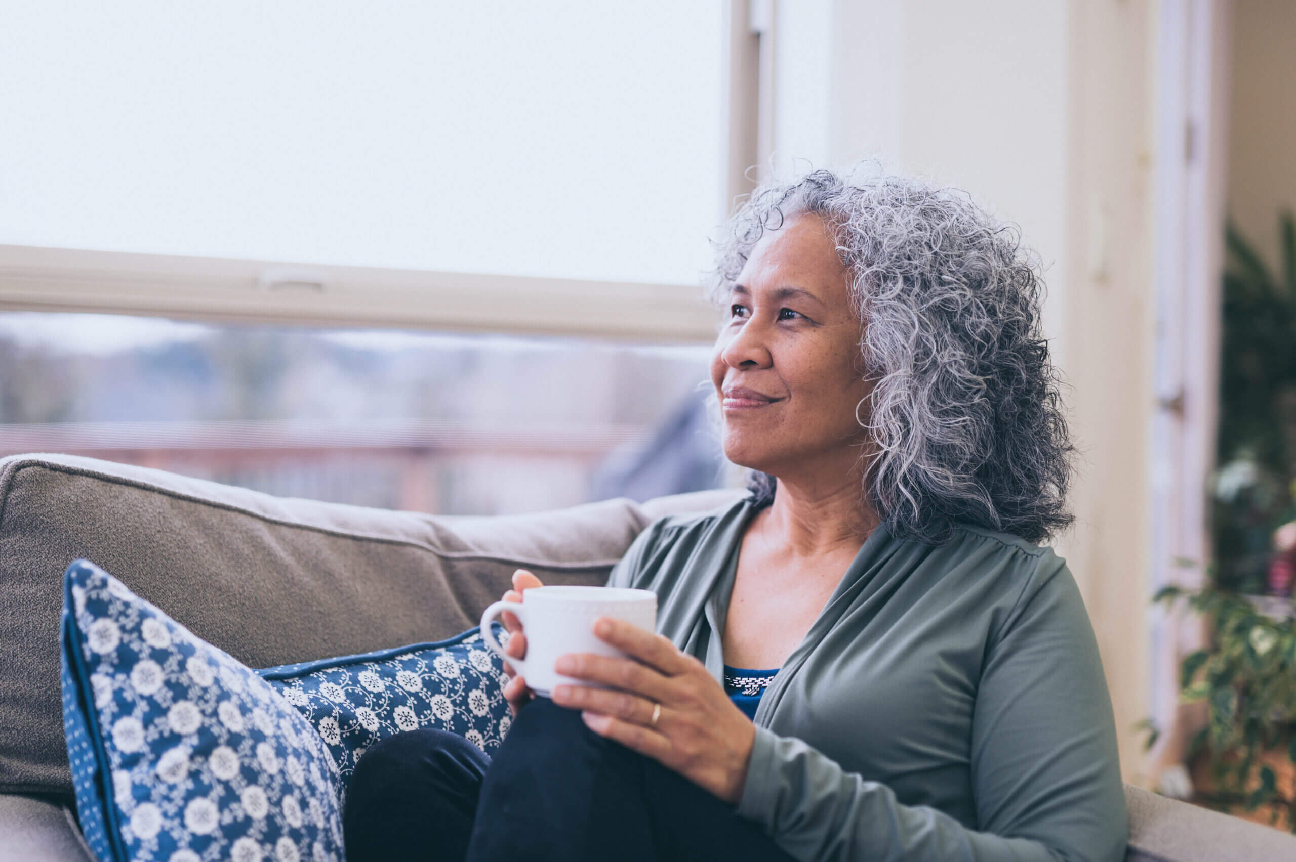 Hawaiian woman drinking coffee inside in morning.