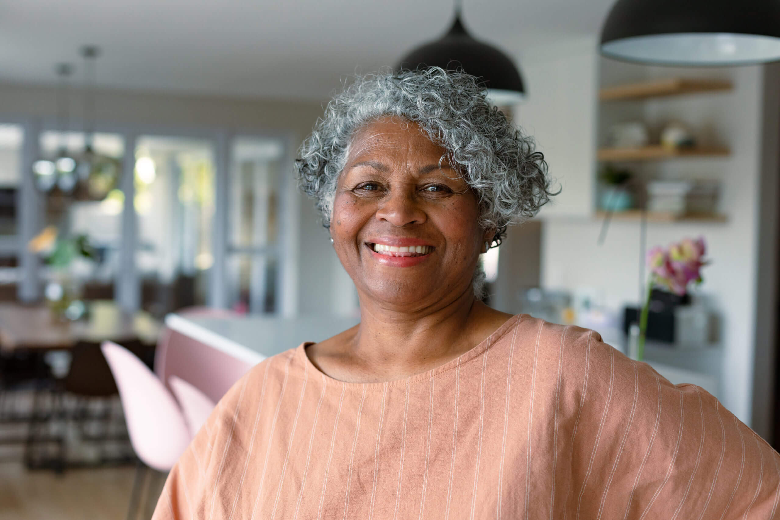 Happy african american senior woman standing standing in kitchen and looking at camera. active retirement lifestyle at home.