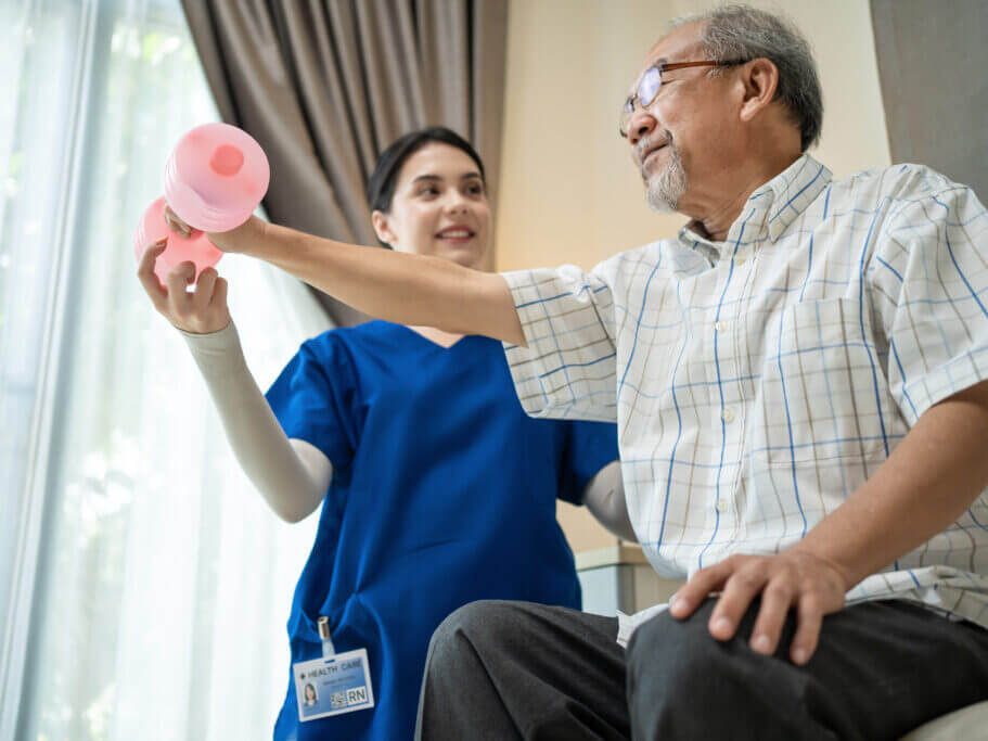 Asian young woman nurse at home nursing care support disabled senior elderly man. Caregiver Therapist serve physical therapy for older patient exercise with dumbbell. Physiotherapist Insurance concept