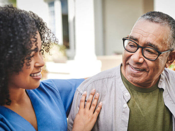 older man with younger woman in nurse's outfit smiling together
